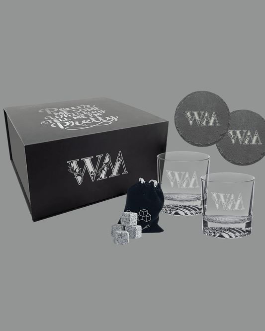 Gifting set with branded glassware, coasters, and decorative items on a gray background- whiskey glasses