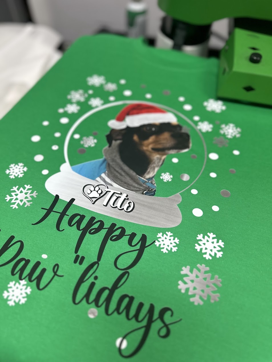Green t shirt with a dog illustration wearing a Santa hat and text 'Happy Pawlidays' 